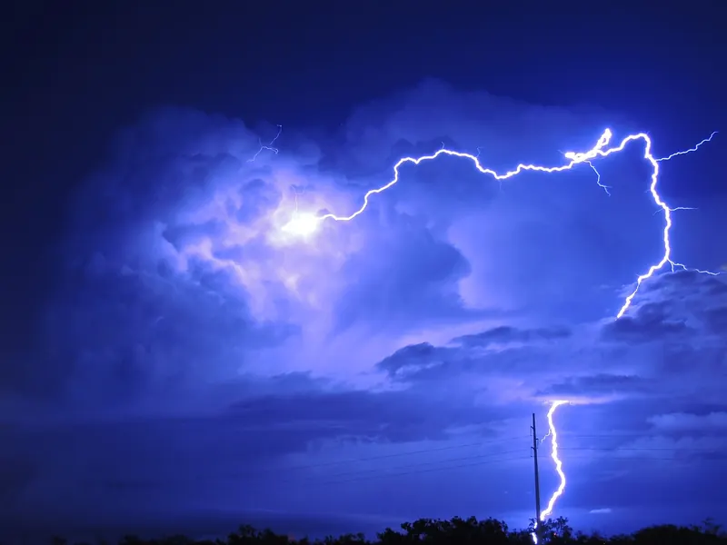 A bright, branching lightning bolt over flat land at night