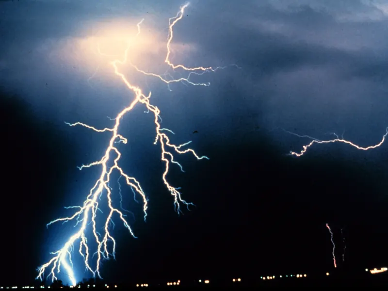 Several forked lightning bolts hitting the ground at night