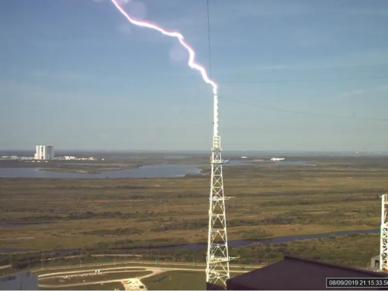 A lightning bolt striking near a launch pad tower at night